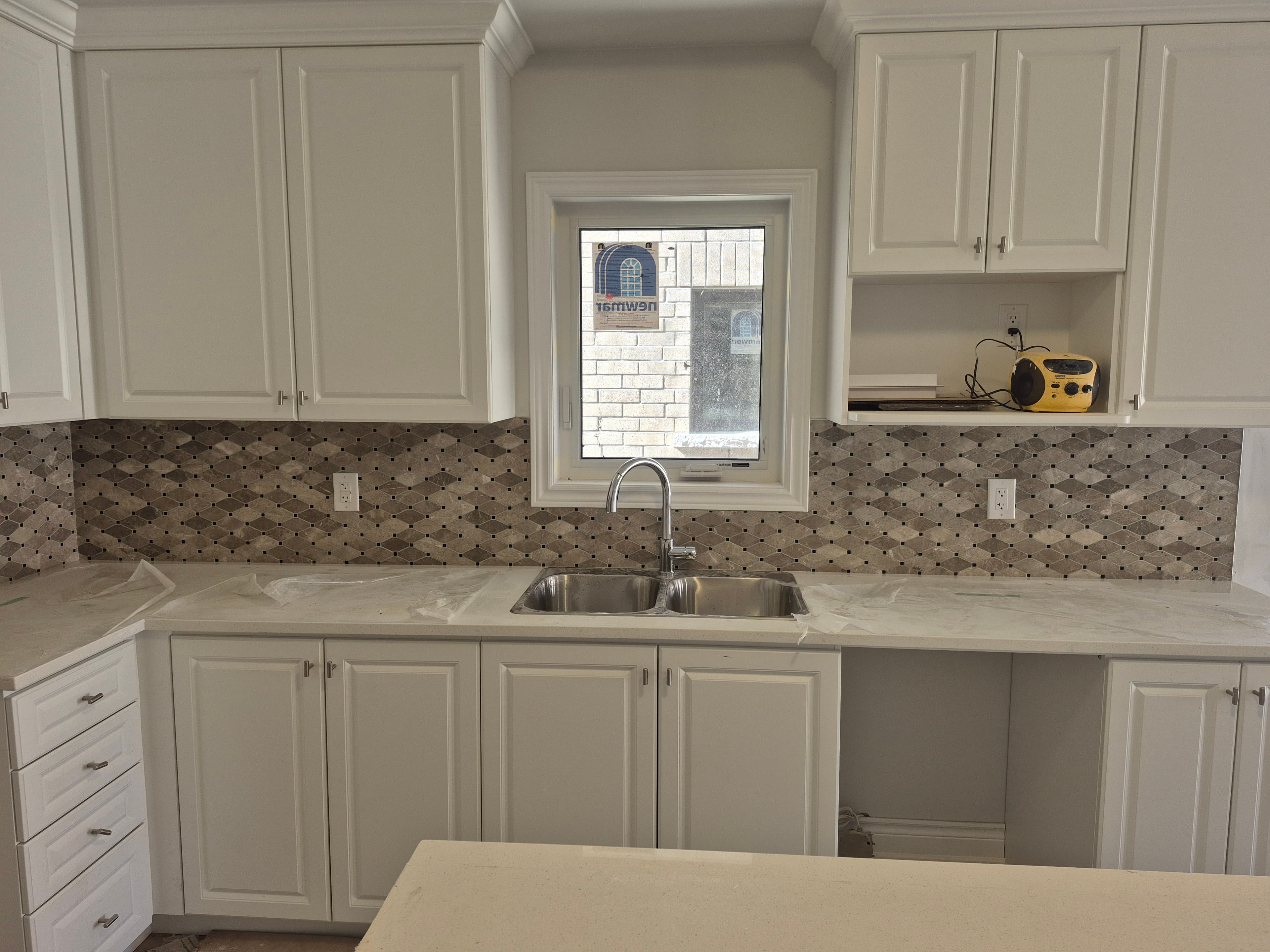 White kitchen cabinets featuring a patterned tile backsplash and a double stainless steel sink.